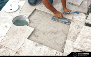 a laborer installing travertine tiles on the floor