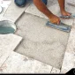 a laborer installing travertine tiles on the floor